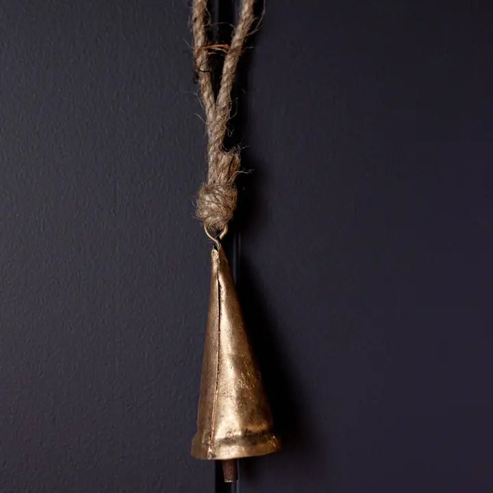 Single elongated bronze tapered Christmas bell ornament hanging against a dark background.