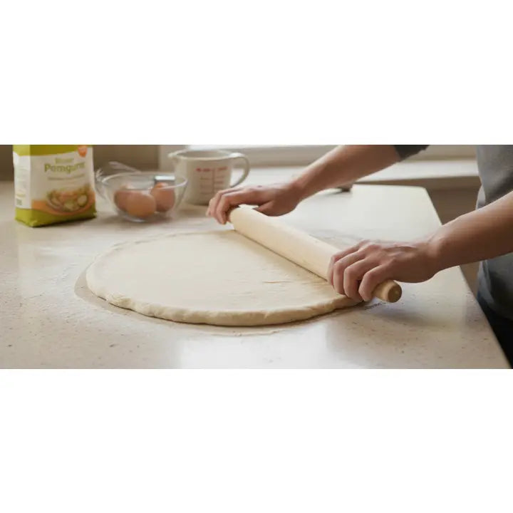 Tapered wooden rolling pin being used to roll dough on a kitchen work surface.