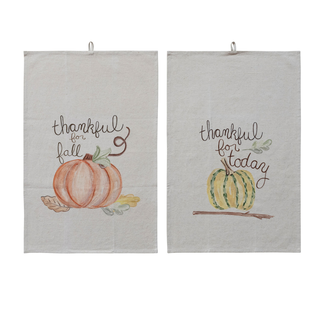 Two light beige fabric hanging kitchen towels with autumn watercolor designs. The left towel reads 'thankful for fall' above an orange pumpkin and leaf.