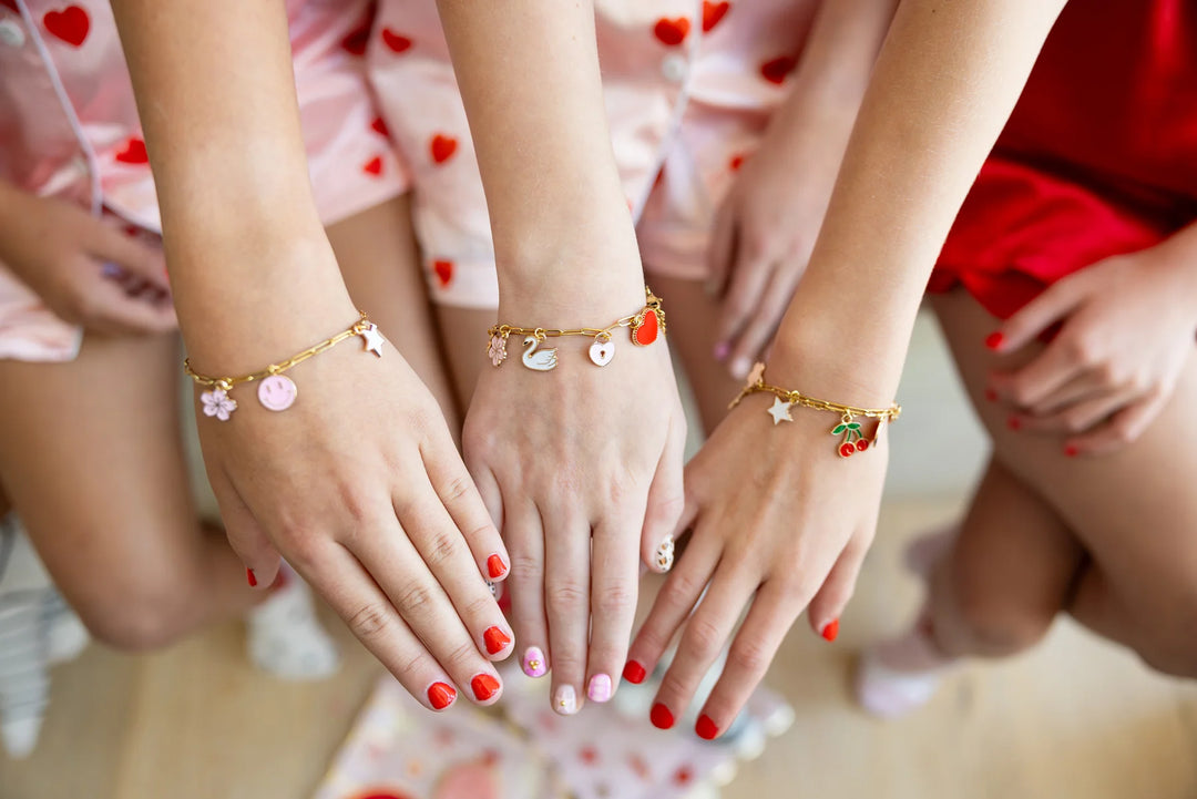 Close-up of hands with colorful bracelets and red nail polish, wearing matching outfits.