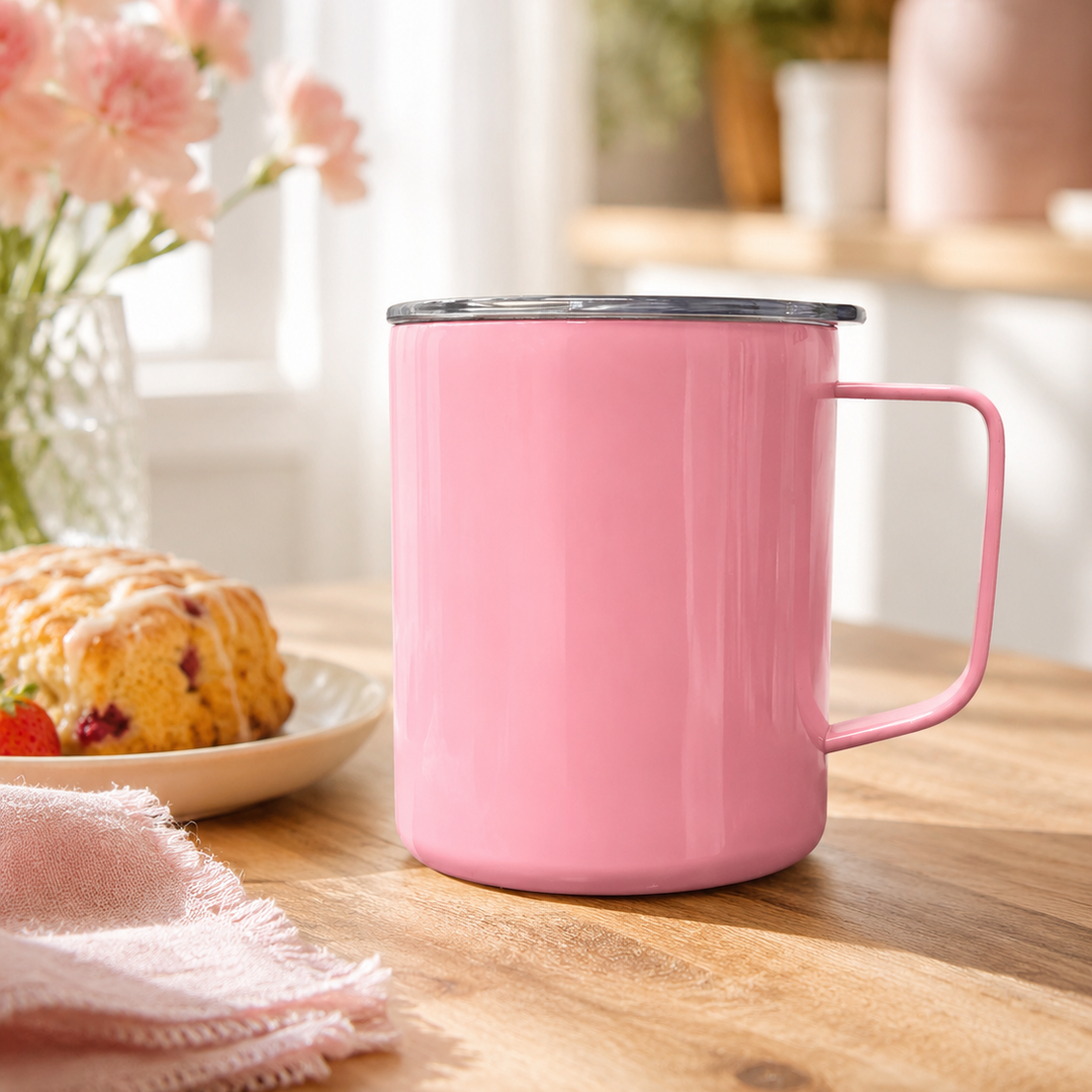 Pink mug on a wooden table with a plate of scones and flowers in the background