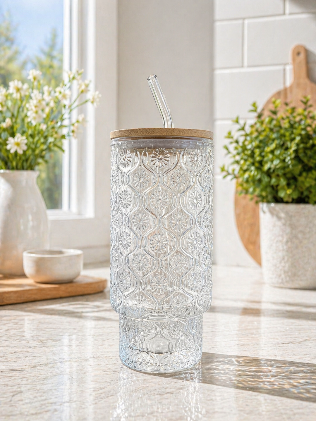 Decorative glass tumbler with a wooden lid on a kitchen counter with plants and a window in the background.