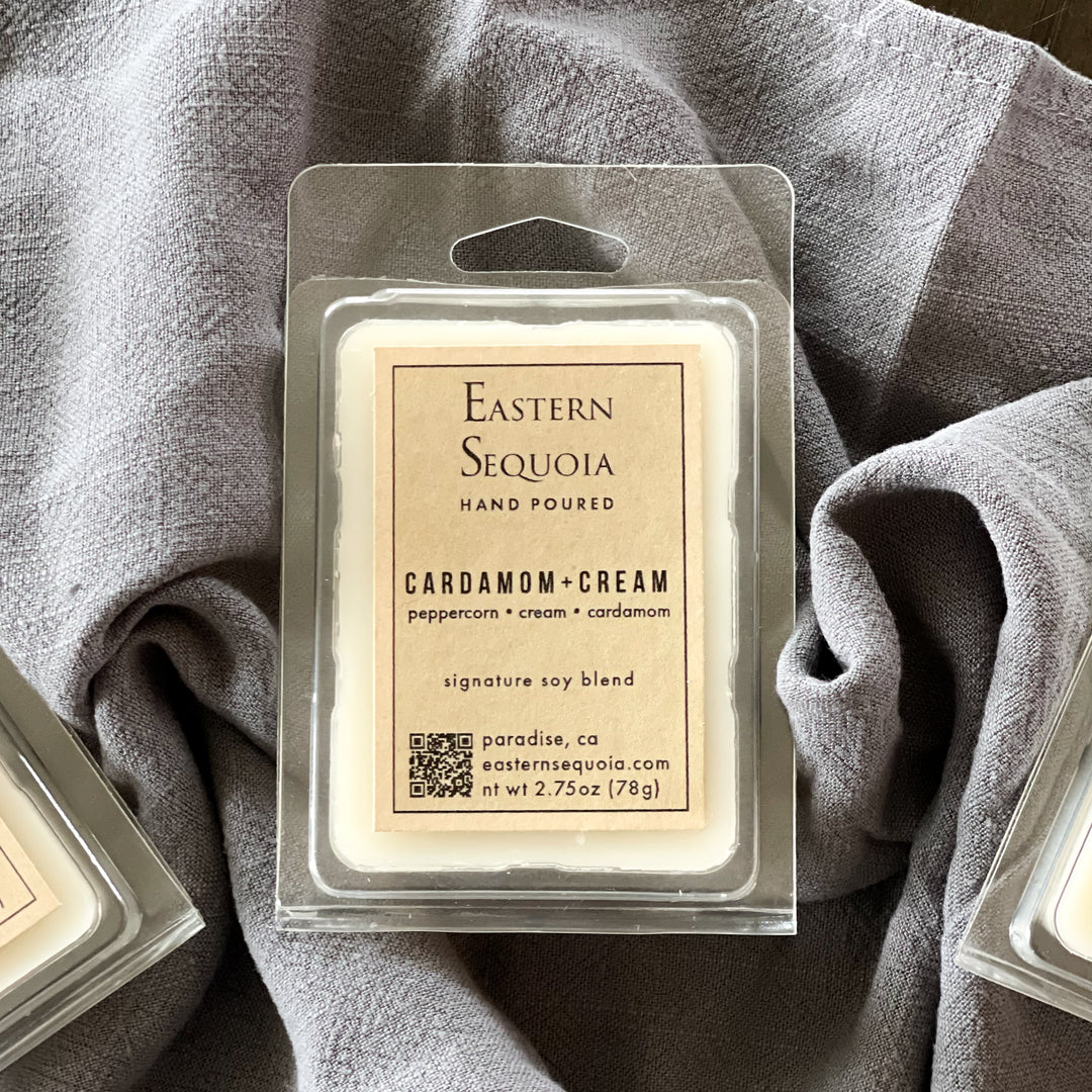 Packaged wax melts labeled 'Eastern Sequoia' with the product name 'Cardamom + Cream' on a gray background.