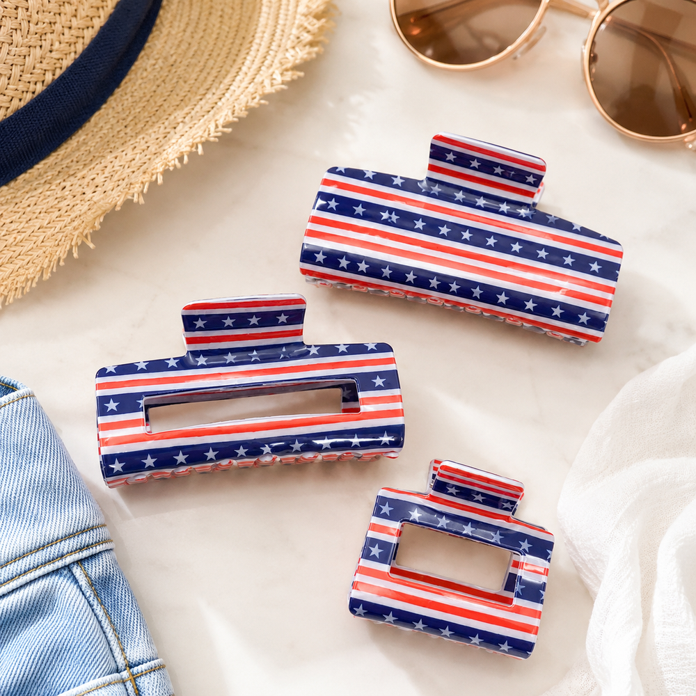 Set of American flag patterned hair clips on a light surface with sunglasses and denim fabric.