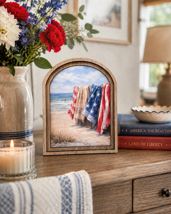 Decorative frame with beach scene on a wooden surface with flowers and books.