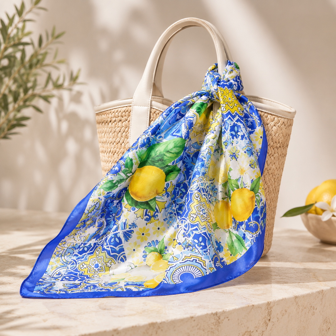 Scarf with lemon design draped over a woven bag on a stone surface.