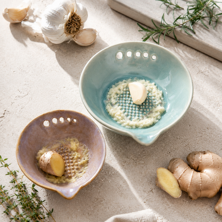 Two ceramic bowls with ingredients on a light surface with herbs and a cloth.