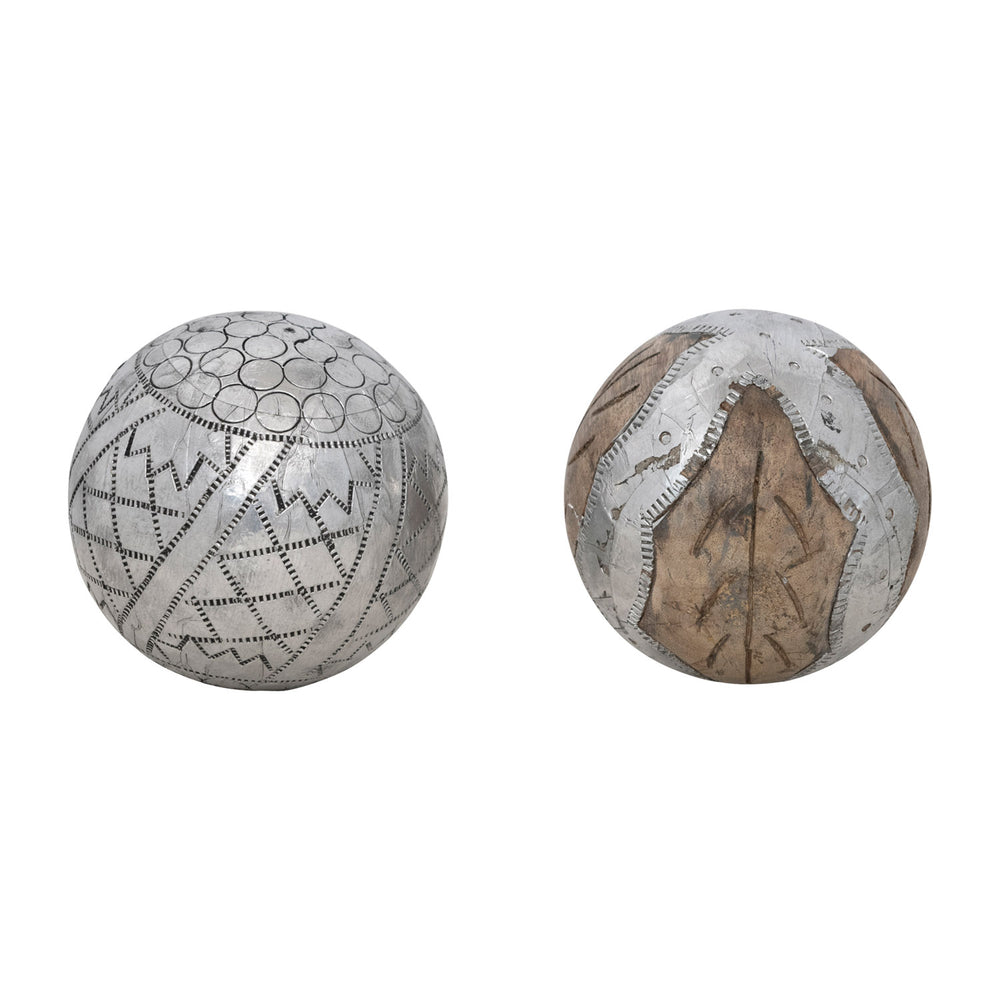 Two decorative spherical objects with engraved geometric patterns, one in polished silver-toned metal and the other in silver-toned metal over brown wood, shown on a plain white background.