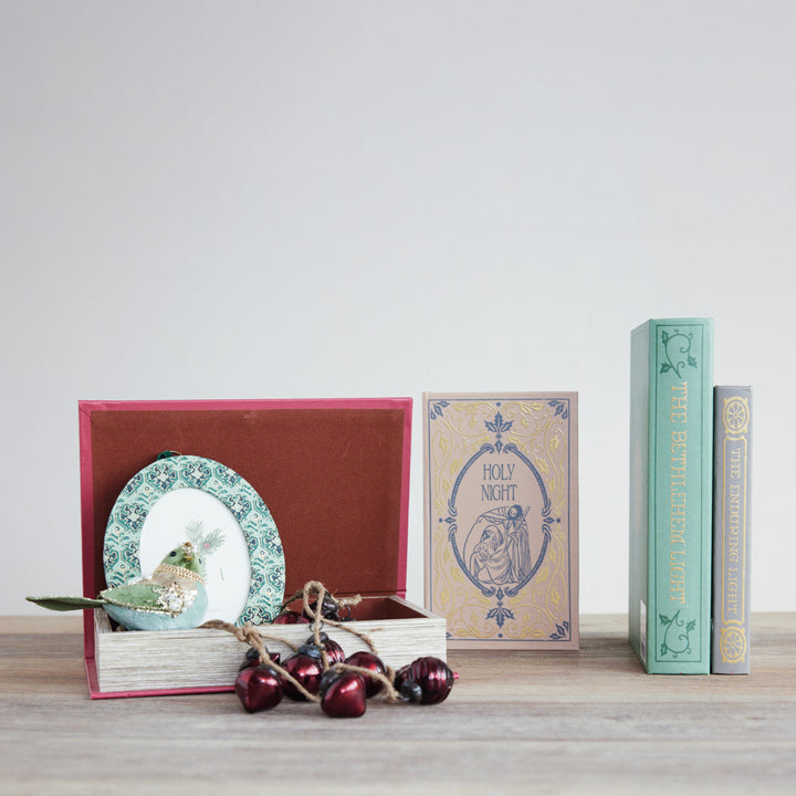 Decorative items including a plate, books, and ornaments on a wooden surface with a light gray background.