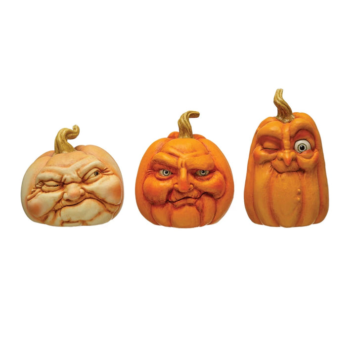 Three resin pumpkins with facial expressions on a white background