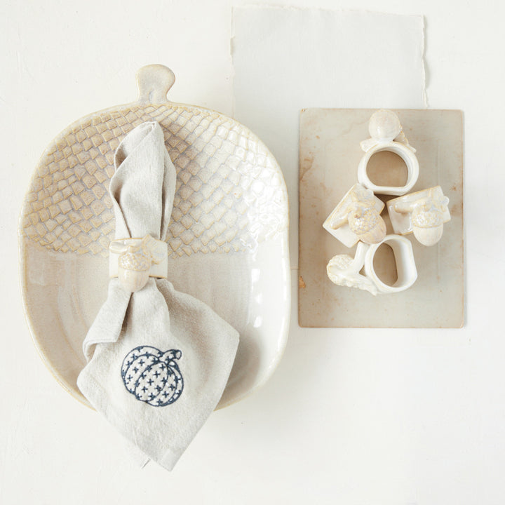 Decorative items including a woven basket, white napkin with a pumpkin design, and wooden blocks with letters on a white background.