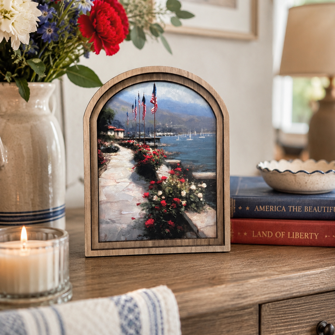 Decorative table setting with a framed landscape print, flowers, and books.