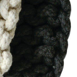 Stack of gray, beige, and black knitted items on a white background