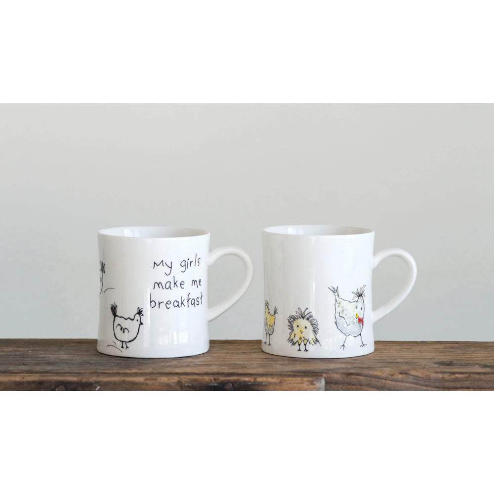 Two white stoneware mugs with chicken illustrations and the text 'MY GIRLS MAKE ME BREAKFAST' on a wooden surface.