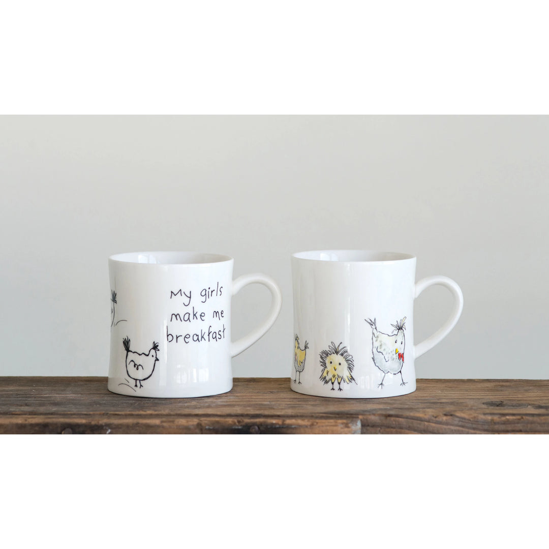 Two white stoneware mugs with chicken illustrations and the text &