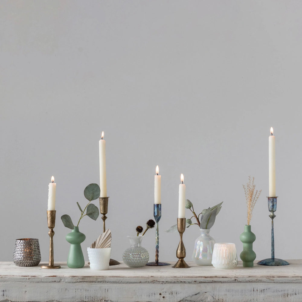 Decorative candles and vases on a wooden surface with a gray wall background