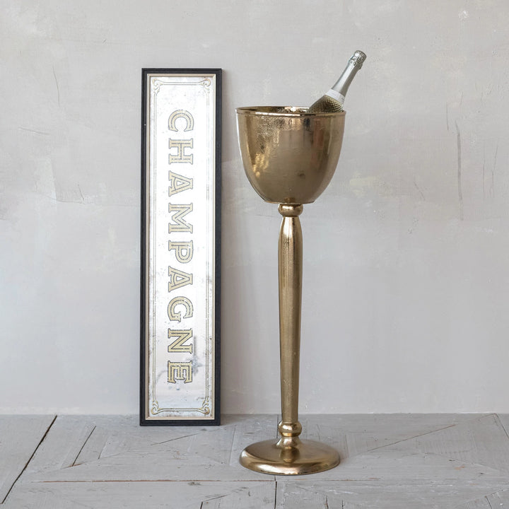 Gold champagne bucket with bottle against a white wall with &