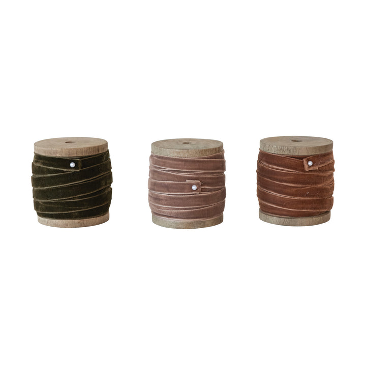 Three wooden spools with brown and black ribbons on a white background