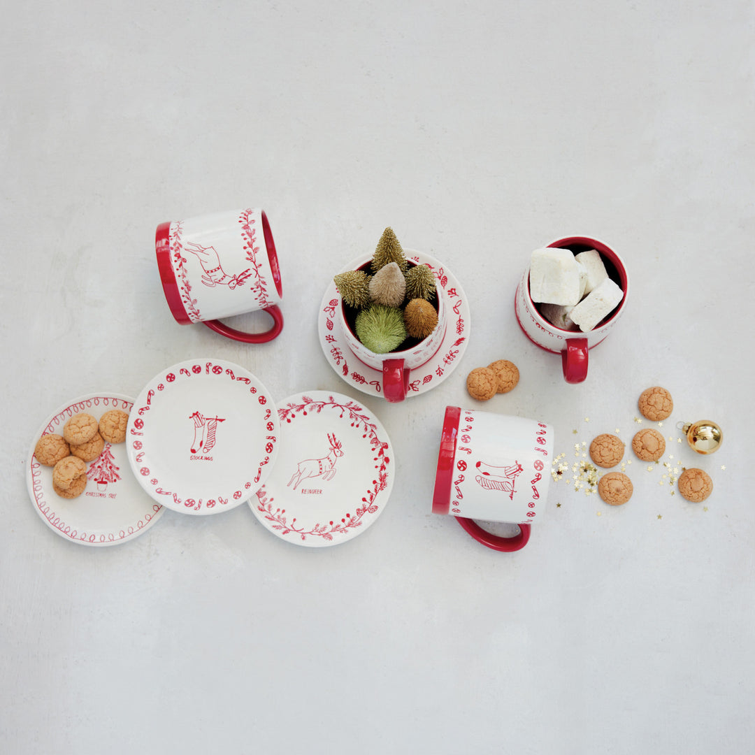 Set of red and white ceramic items including cups, saucers, and a small plant on a light gray background.
