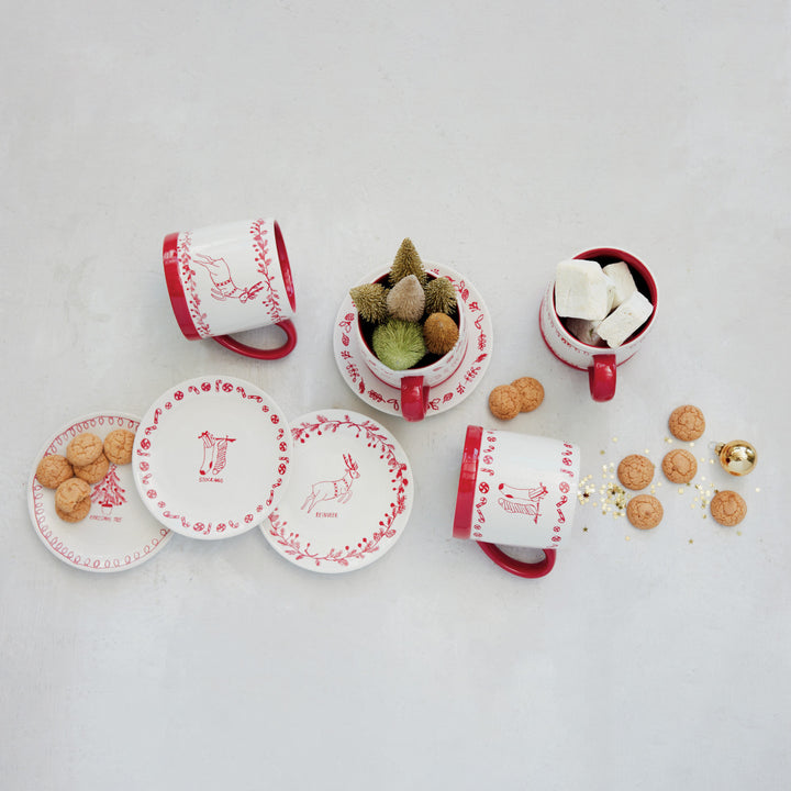 Set of red and white ceramic items including cups, saucers, and a small plant on a light gray background.
